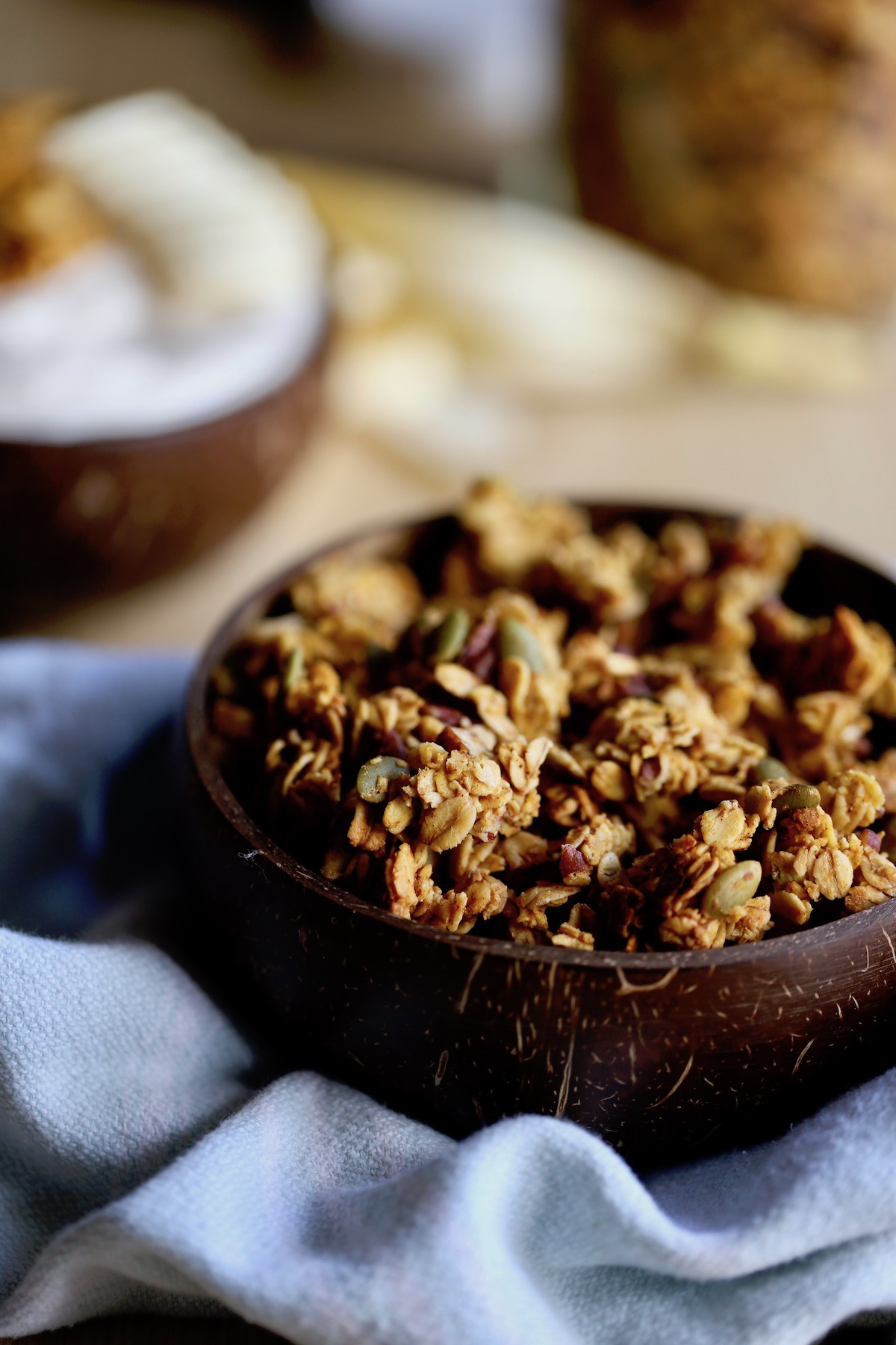 golden brown pumpkin granola filling up a coconut bowl