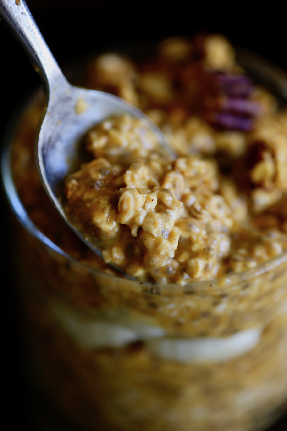a spoon scooping up some creamy vegan pumpkin pie overnight oats with chia seeds
