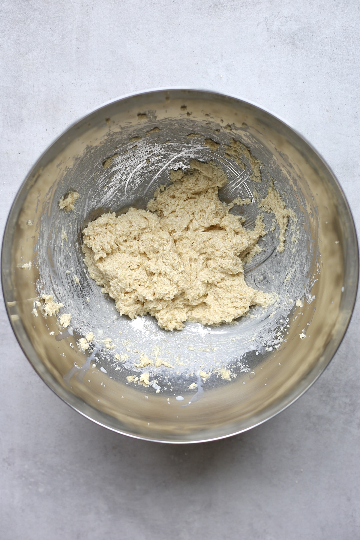 An overhead shot of butter and sugar after they have been creamed together in a large silver mixing bowl.