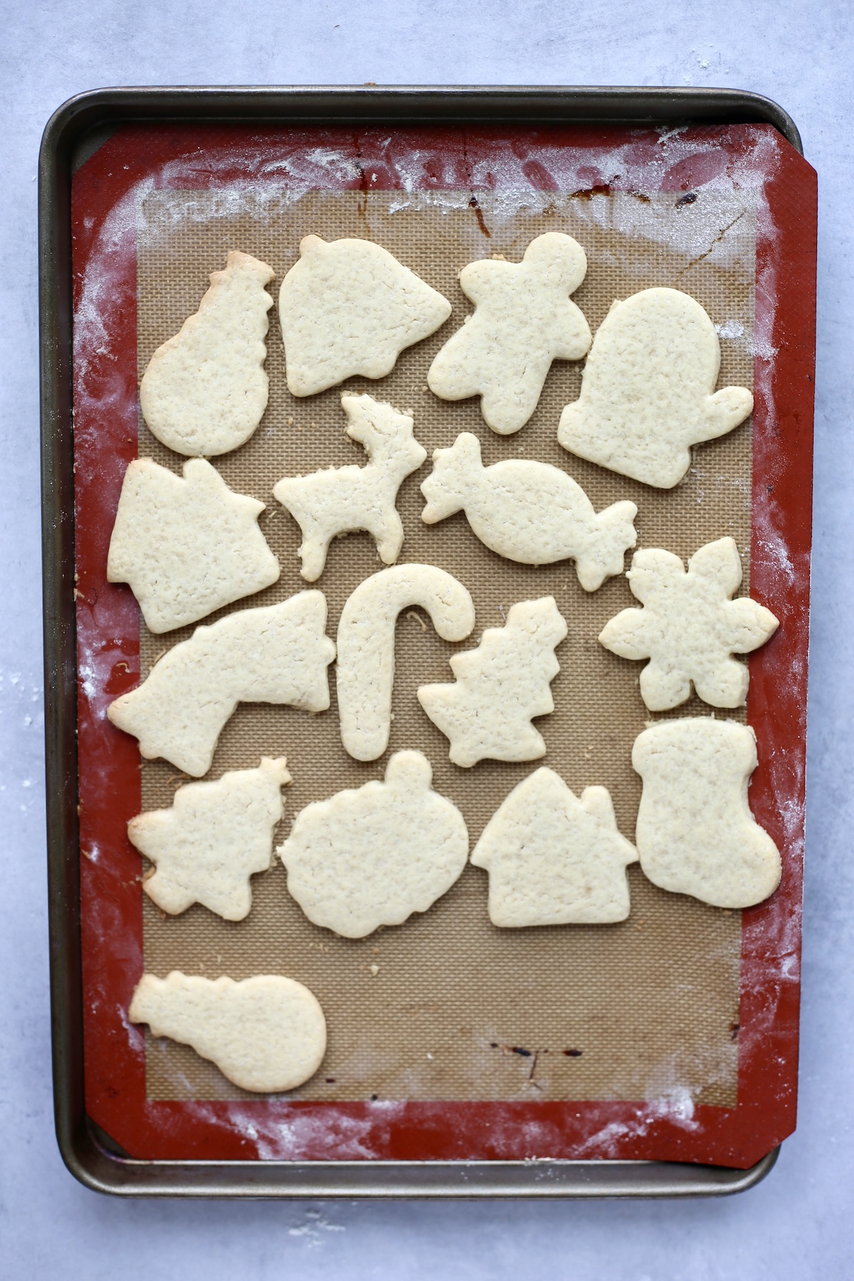 An overhead shot of vegan Christmas sugar cookies on a baking sheet lined with a silicone baking mat.