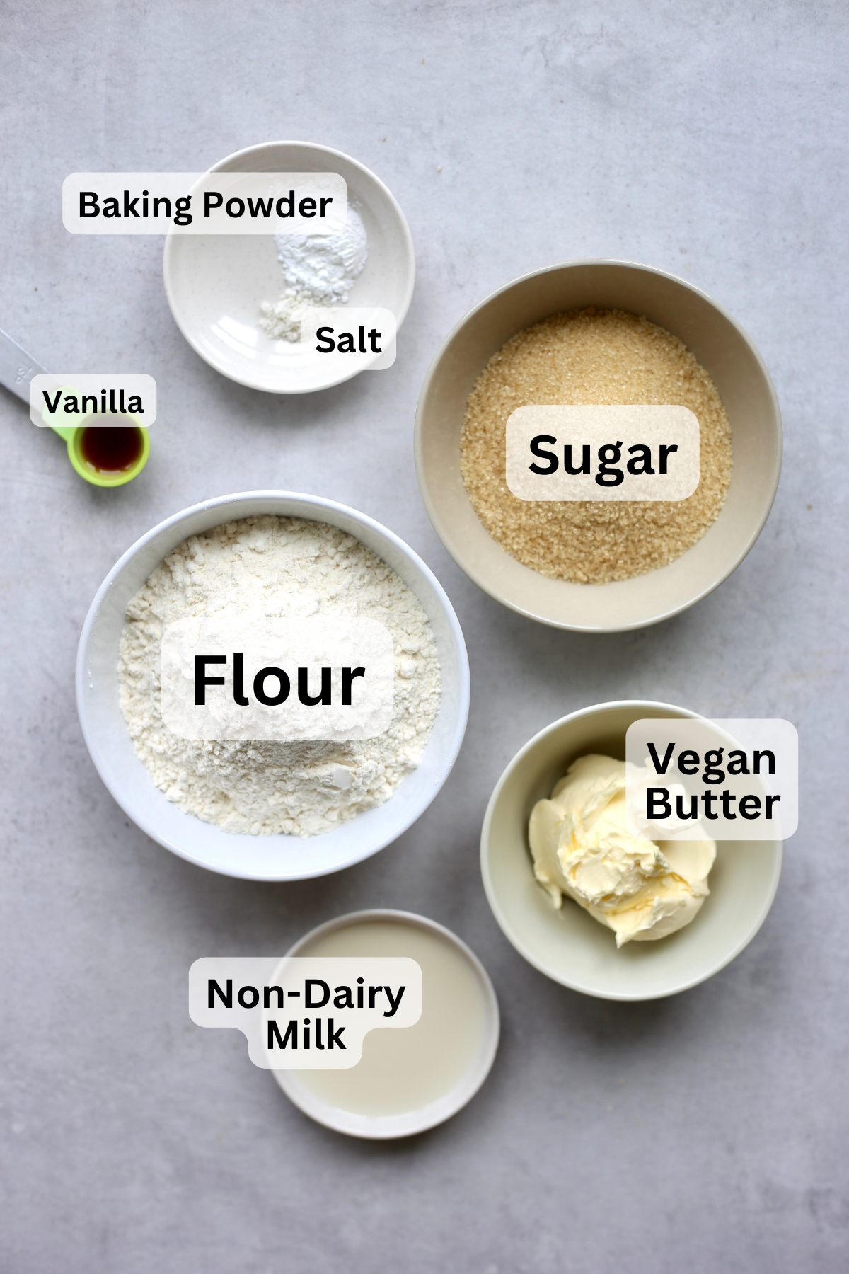 Flour, sugar, vegan butter, non-dairy milk, salt, baking powder and vanilla measured out into bowls for making vegan sugar cookies.