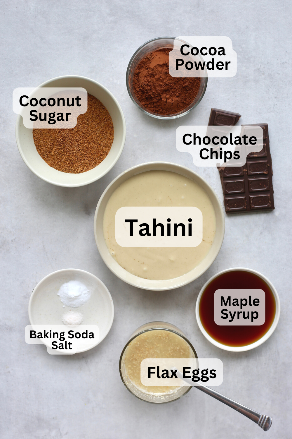 Tahini, coconut sugar, cocoa powder, chocolate, maple syrup and flaxseeds measured out into bowls to make tahini brownies.