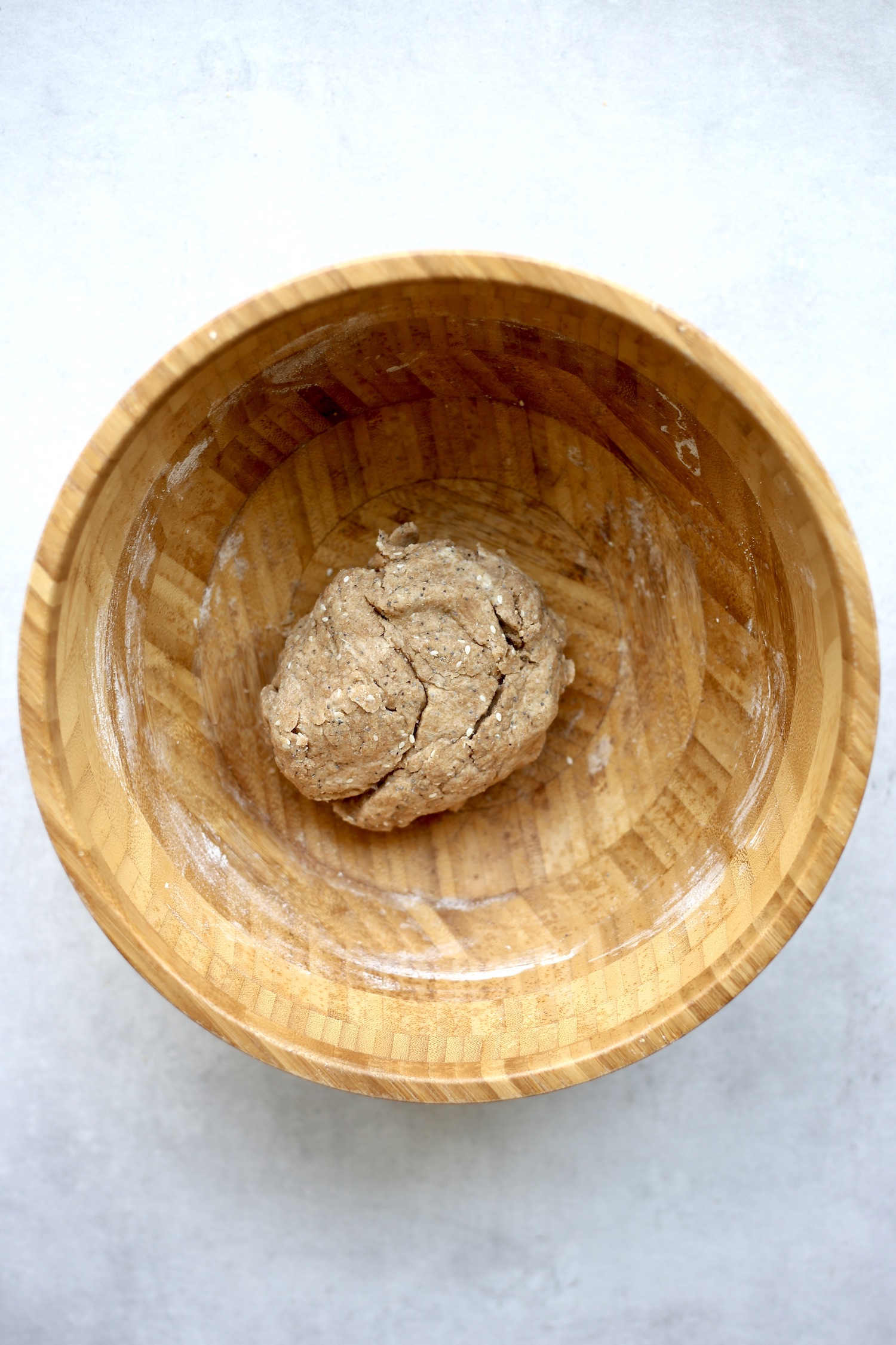 The dough for whole wheat crackers resting in a large wooden mixing bowl. 