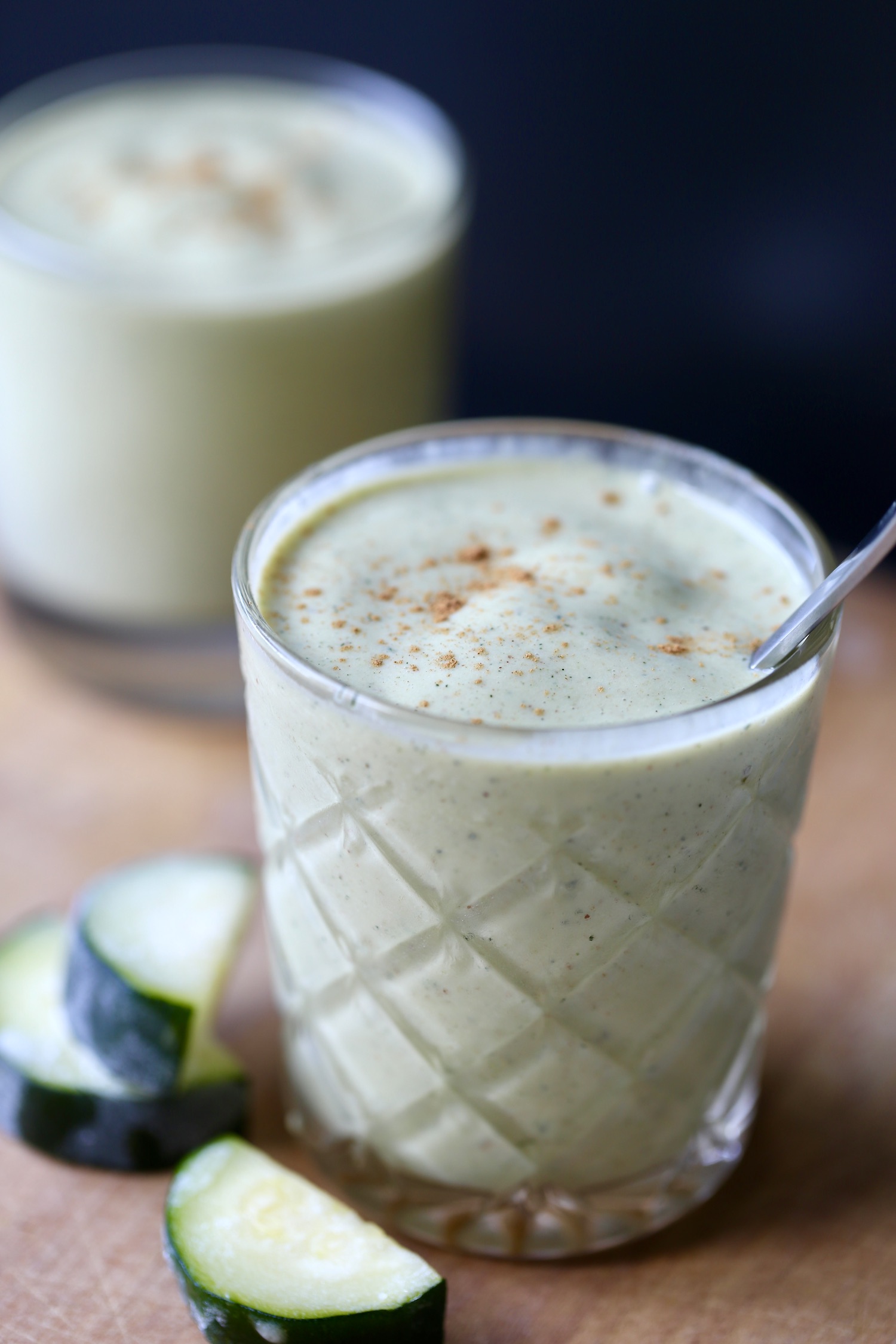 Two zucchini smoothies in glasses with cinnamon sprinkled on top. 